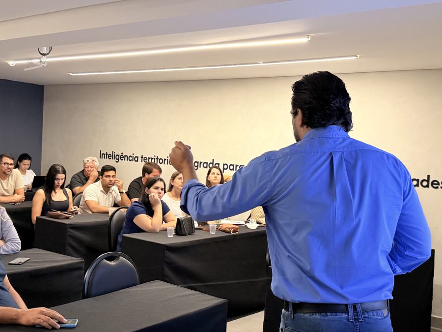 Instrutor de costas gesticula diante da turma, sob a frase Inteligência territorial integrada na parede.