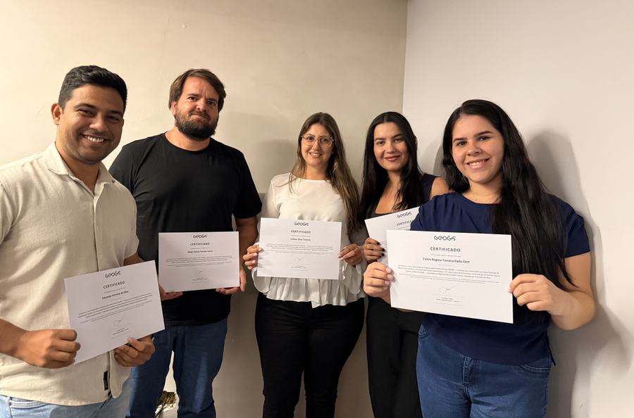 Cinco participantes posam lado a lado exibindo os certificados de conclusão.